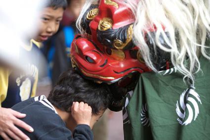 お正月　獅子舞に頭をかじられる子ども