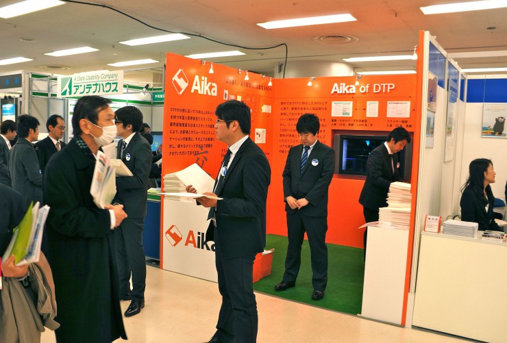 自社ブース前で資料を配る大連愛科社員